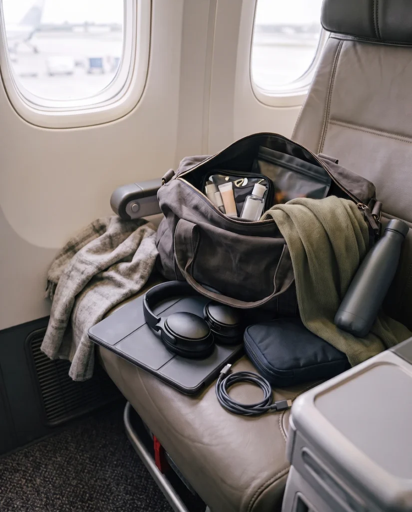 Personal item essentials arranged on an airplane seat for a long flight